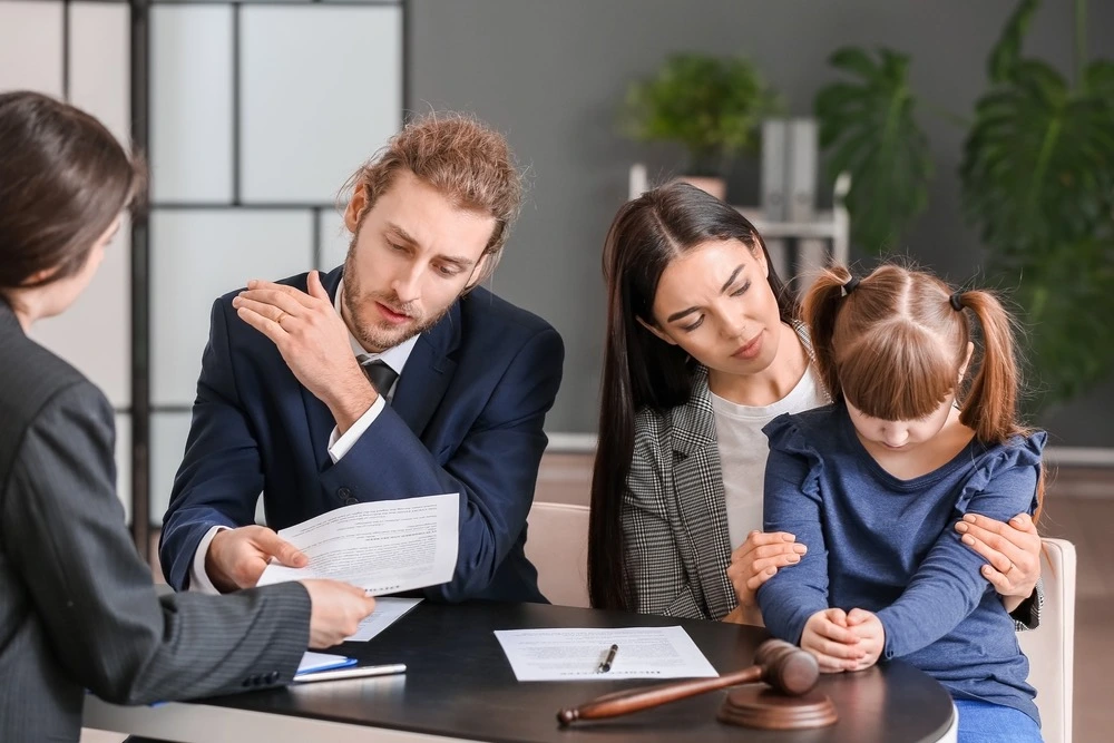 A family with a child in a law office, signing a notarized legal document.