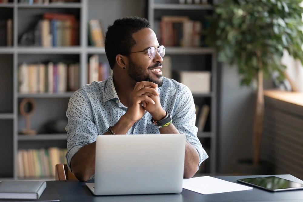 A smiling person sits behind a laptop, representing recovery success under the Marchman Act.